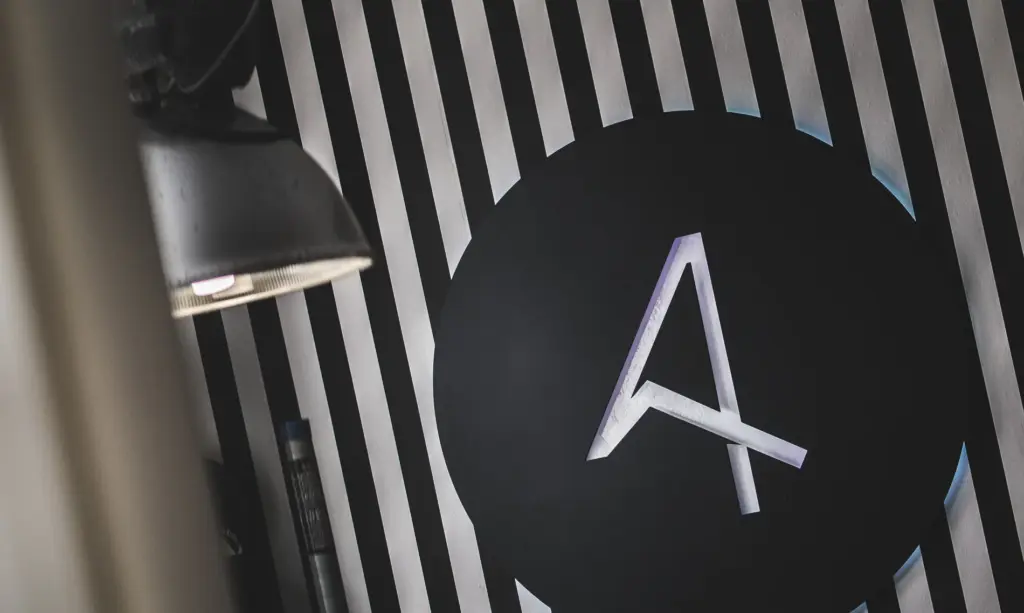 Logo der Agentur Ausdruckslos an einer schwarz-weiß gestreiften Wand mit Lampe