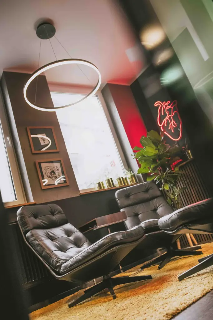 Sitzecke mit zwei Ledersesseln, Ringleuchte und Neon-Herz im Büro der Agentur Ausdruckslos