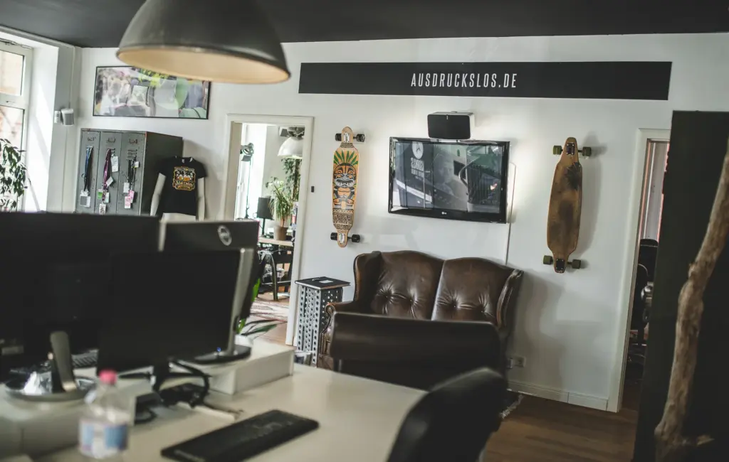 Arbeitsplatz, Ledersofa und Longboards an der Wand im Büro der Agentur Ausdruckslos
